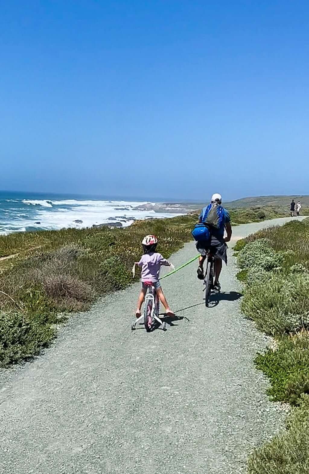 father pulling daughter on bike with bungee