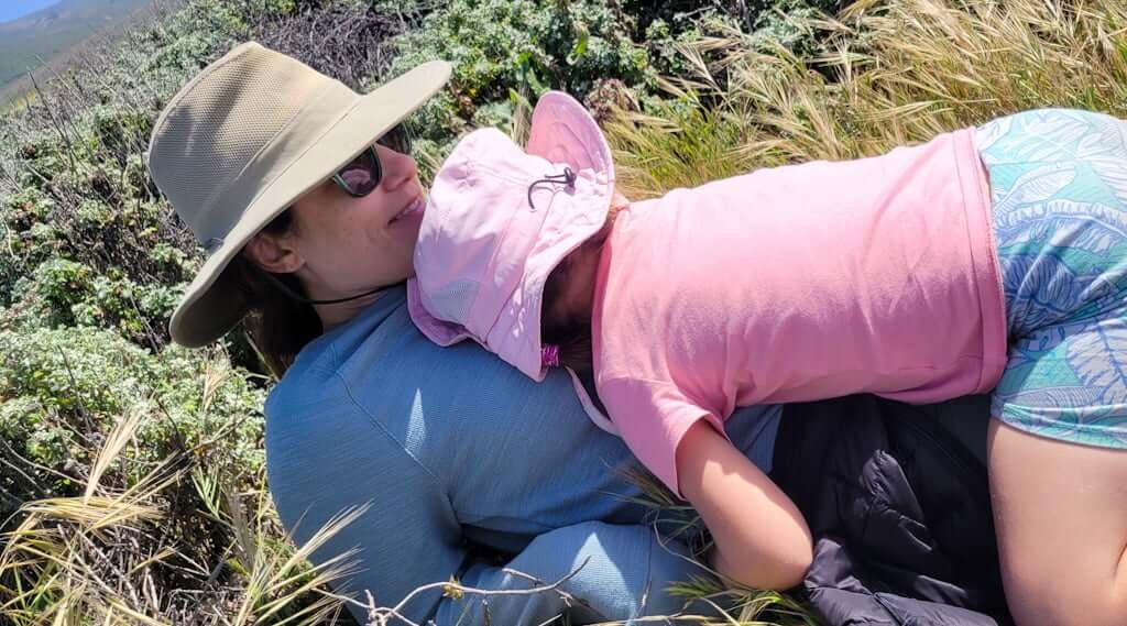 daughter cuddling mother in wild grass