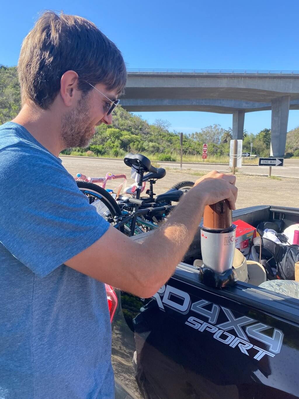 man blending a chocolate shake in the back of his truck alongside the road because he loves his wife