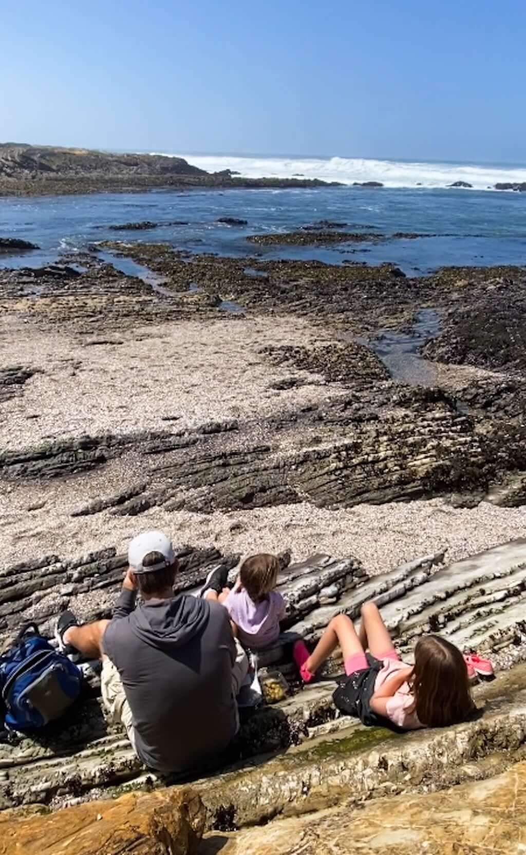 family eating a snack on rocks next to tidepools