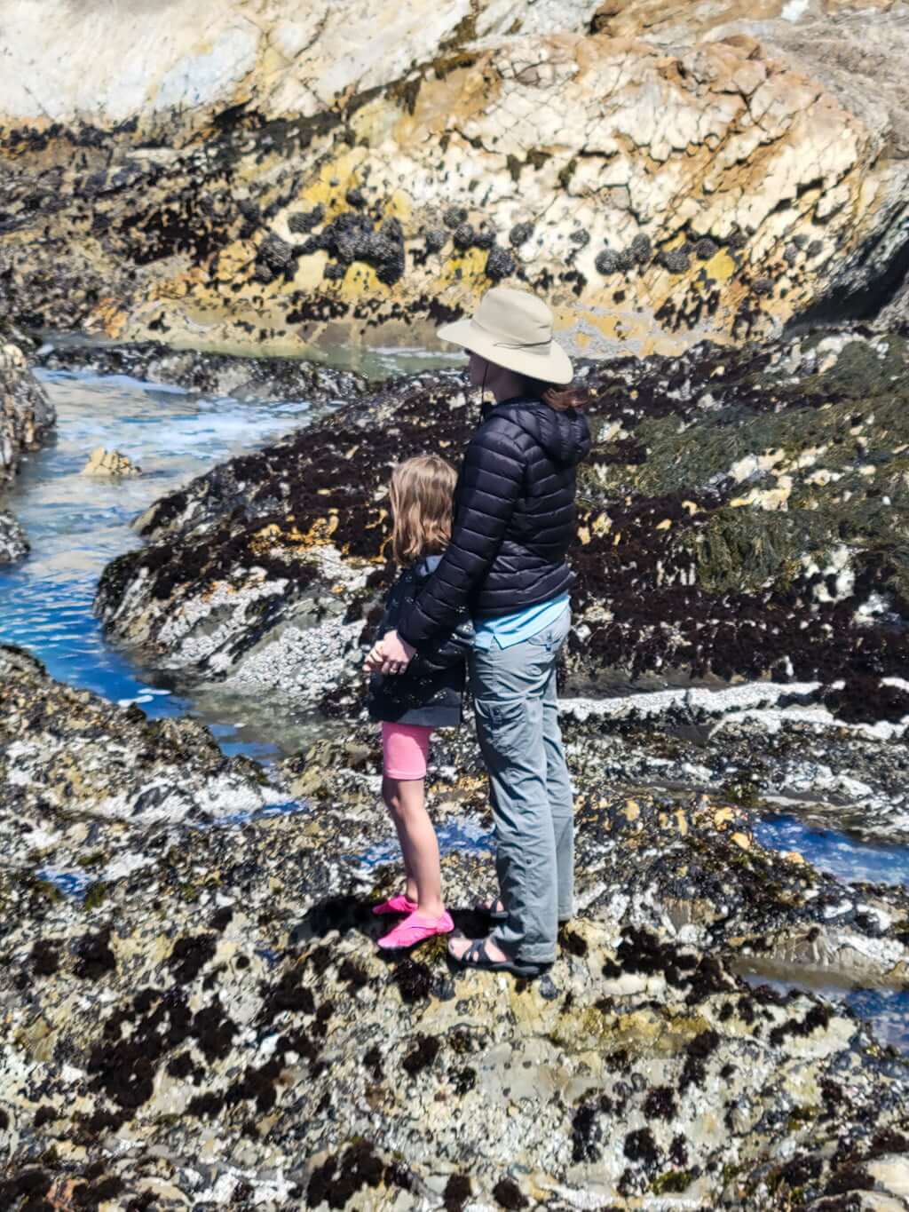 mother and daughter standing on rock surrounded by tidepools