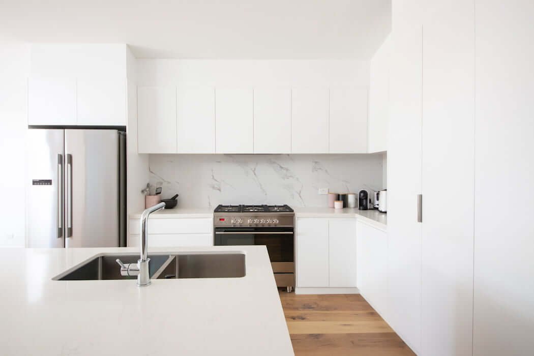 white minimalist kitchen created on a budget with simple marble backsplash