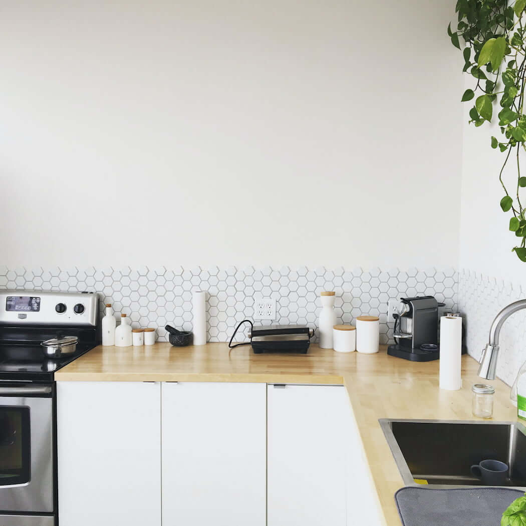 small white IKEA kitchen with wood countertops and small backsplash tile hexagon, white budget kitchen