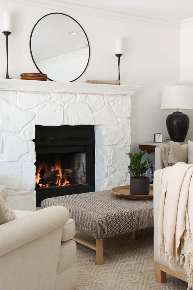 painted stone fireplace with fire going and ottoman coffee table