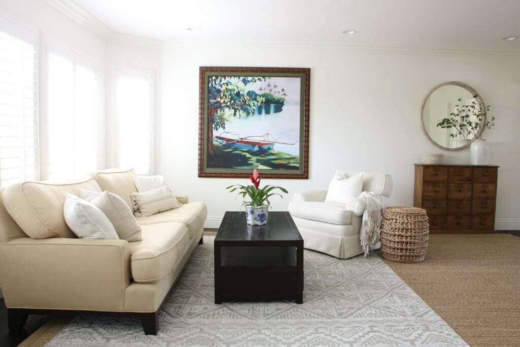 neutral formal living room with dark furniture and coastal artwork and woven furniture