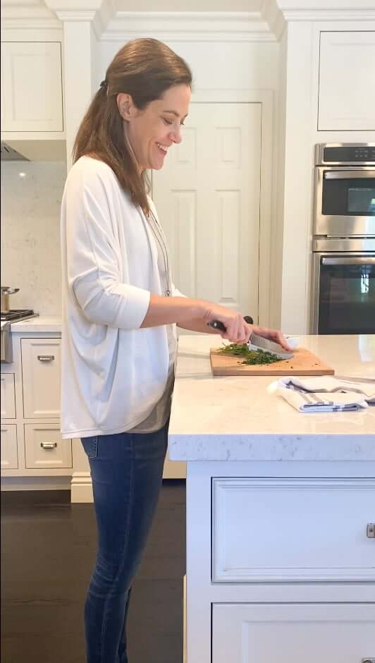 woman chopping cilantro at kitchen counter