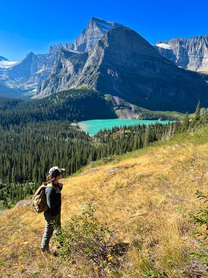 woman hiking in Glacier National Park, Montana with glacial lake and mountain in distance