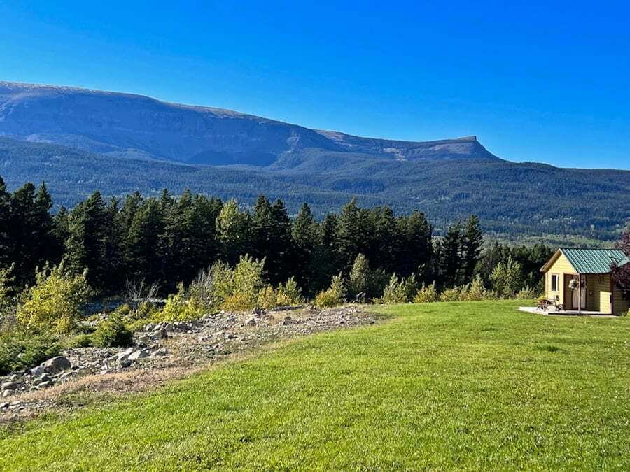 cabin with grass and mountains lodging in Glacier National Park