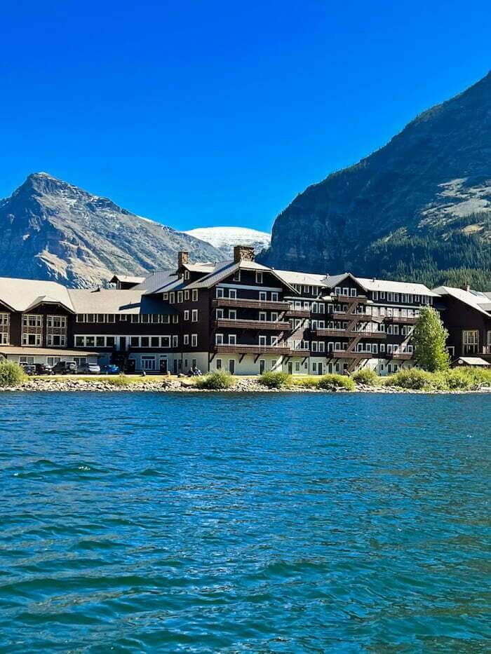 Many Glacier Hotel with lake in foreground and mountains in distance