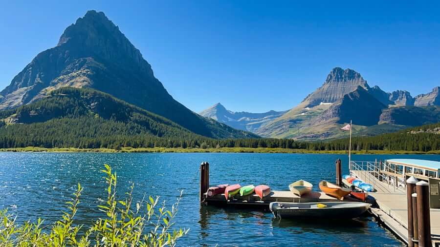 view from Many Glacier Hotel and boat dock with mountains in distance with lake