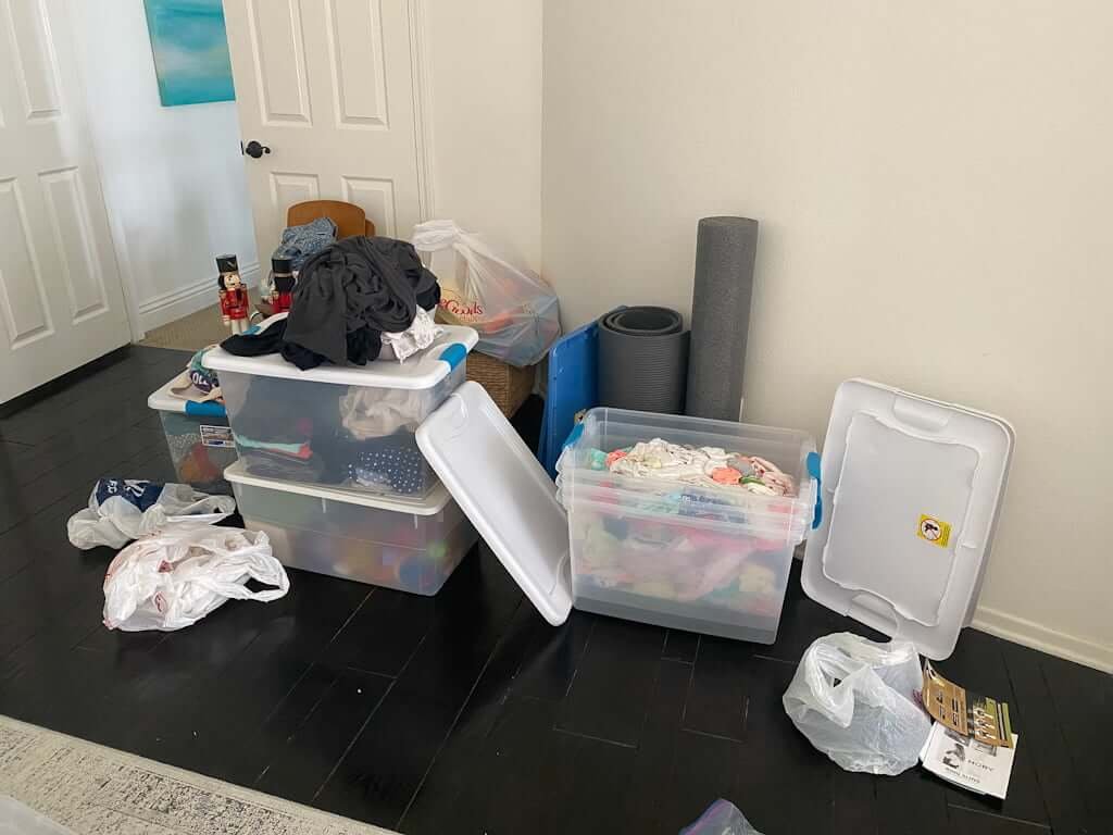 bedroom with plastic moving tubs full of baby items