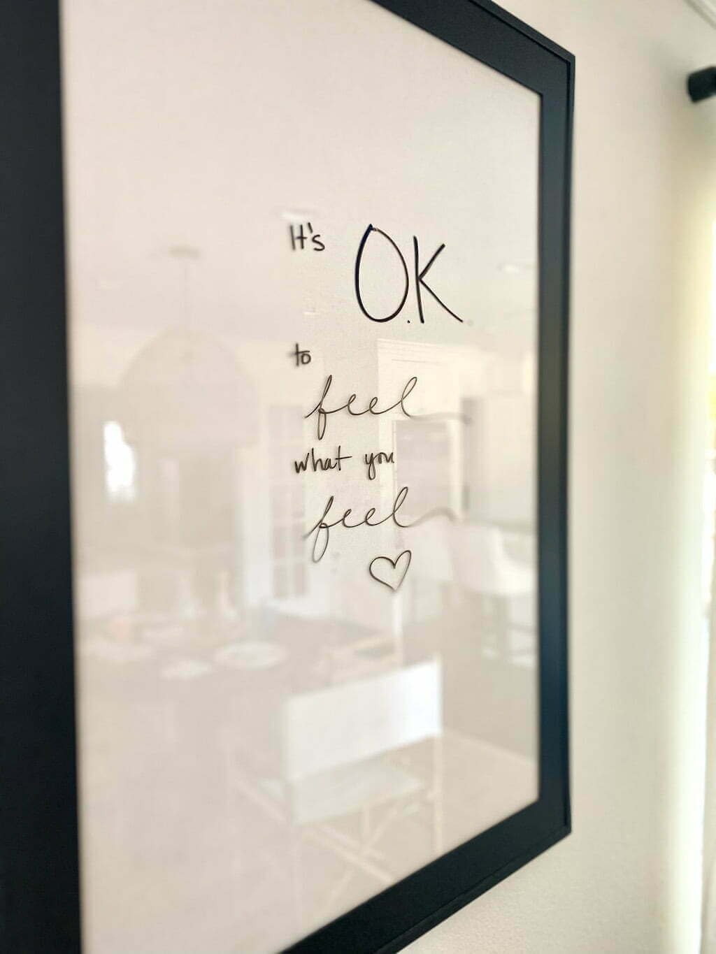 glass frame on wall reads "It's OK to feel what you feel"