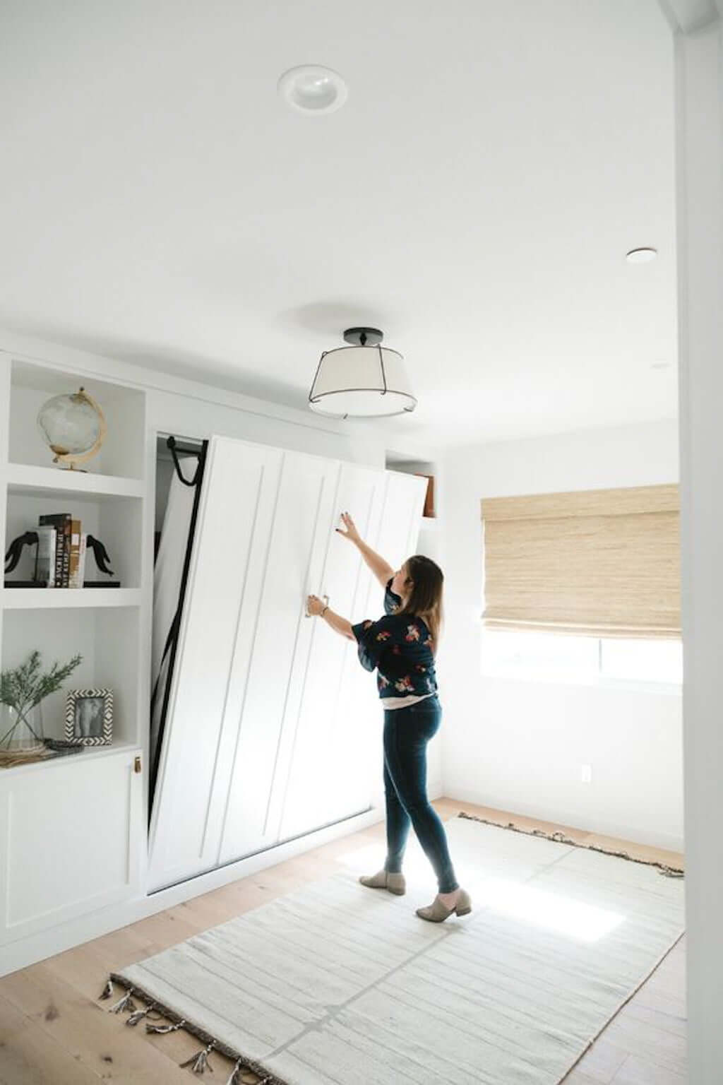 woman folding up white murphy bed into wall