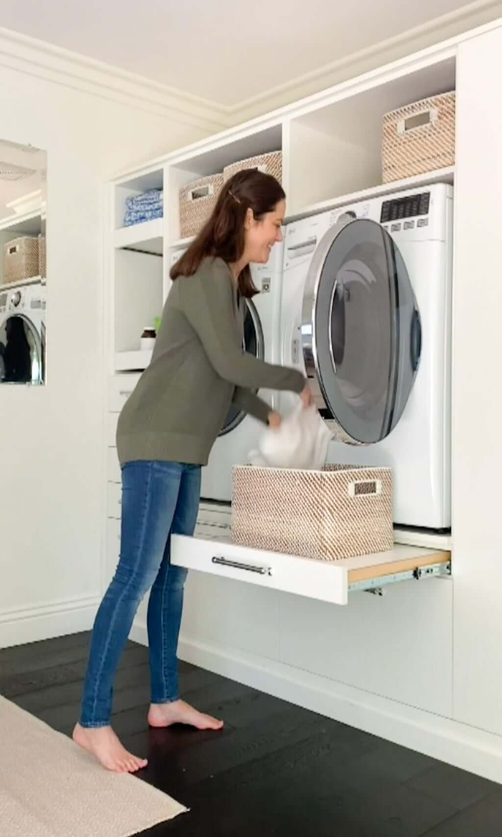 woman at washer machine and dryer pulling out clean clothing