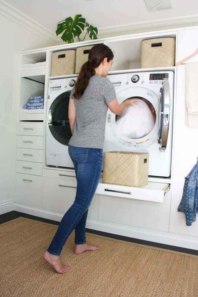 woman pulling clean white towels out of laundry machine