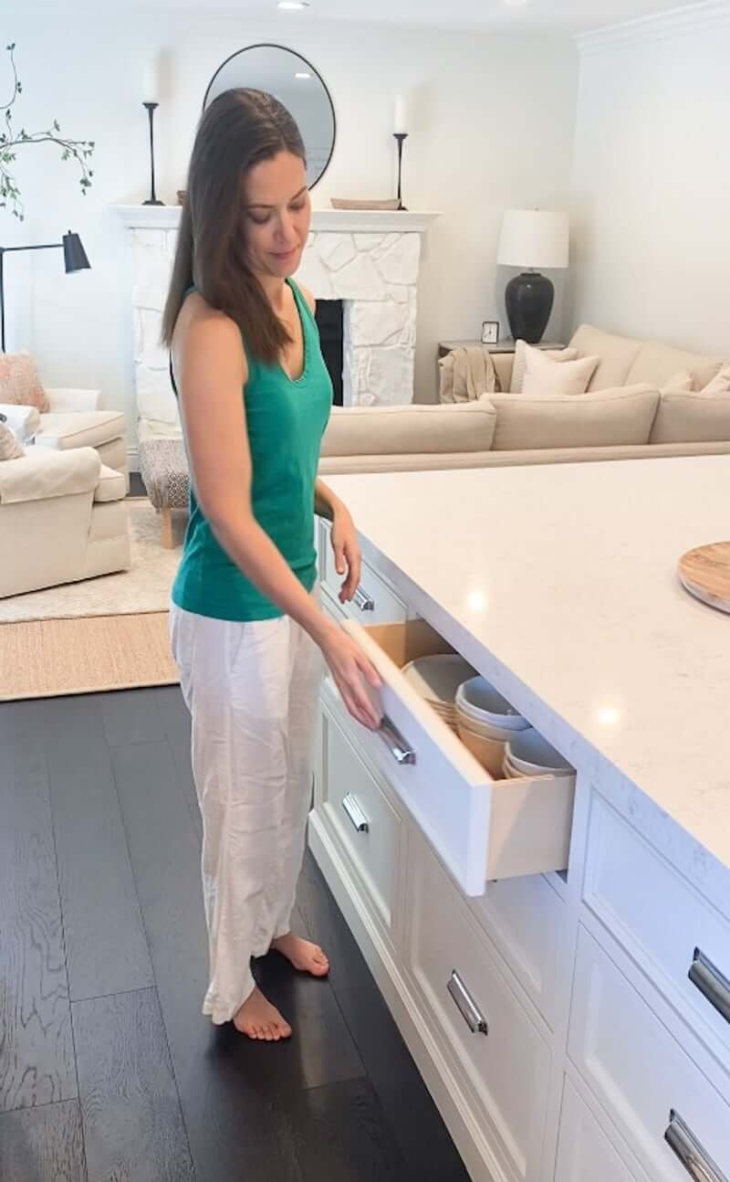 women opening drawer in kitchen with plates