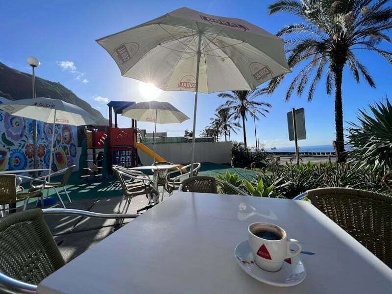 espresso on cafe table next to beach playground by ocean
