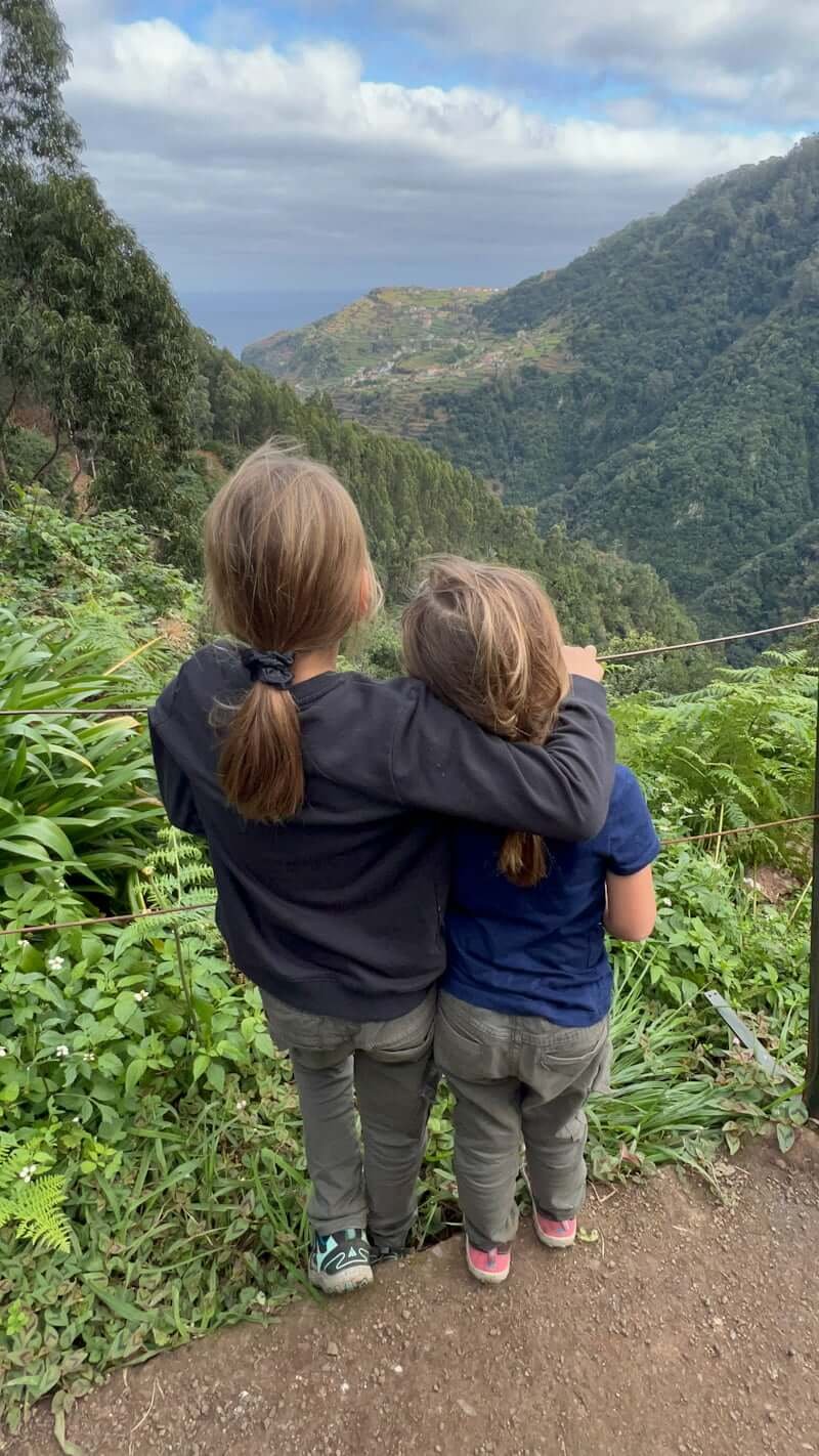 two girls hugging while hiking looking at view in Madeira, Portugal