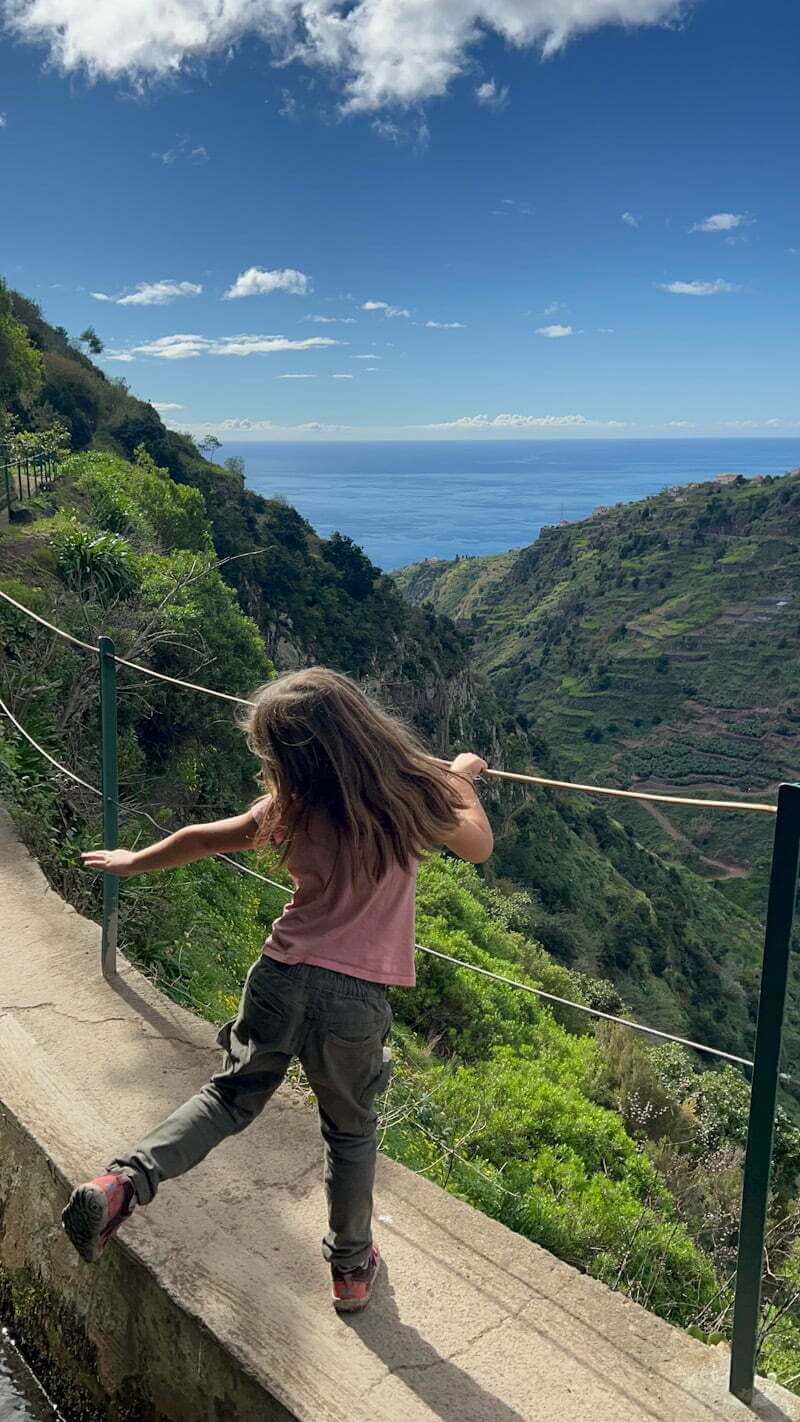girl dancing while hiking with ocean in distance