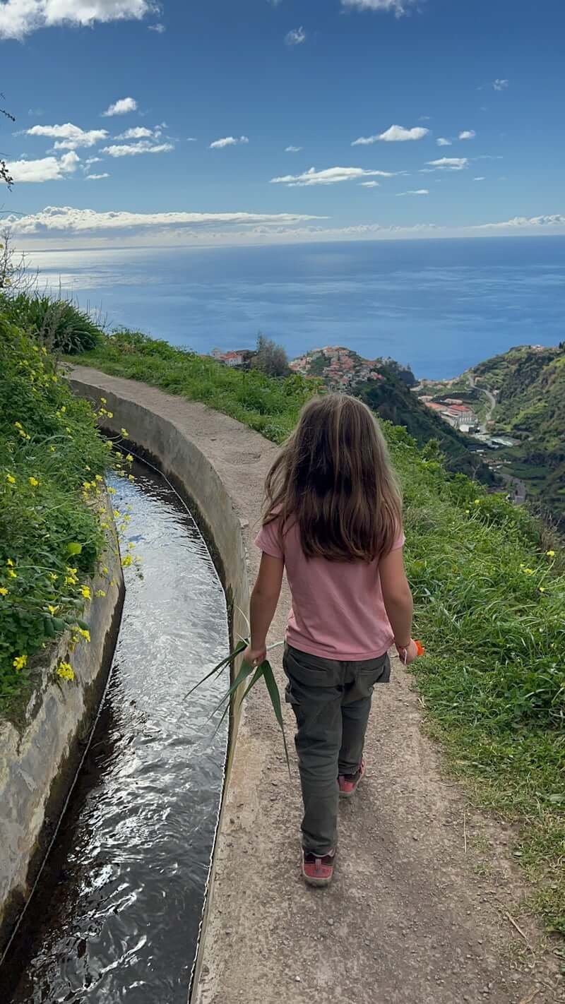 girl hiking along levada in Madeira with ocean in distance