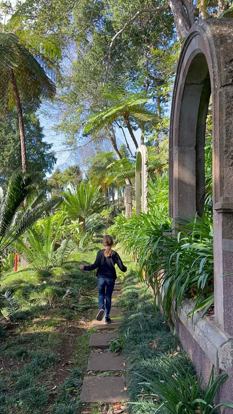 girl running down pathway with plants around