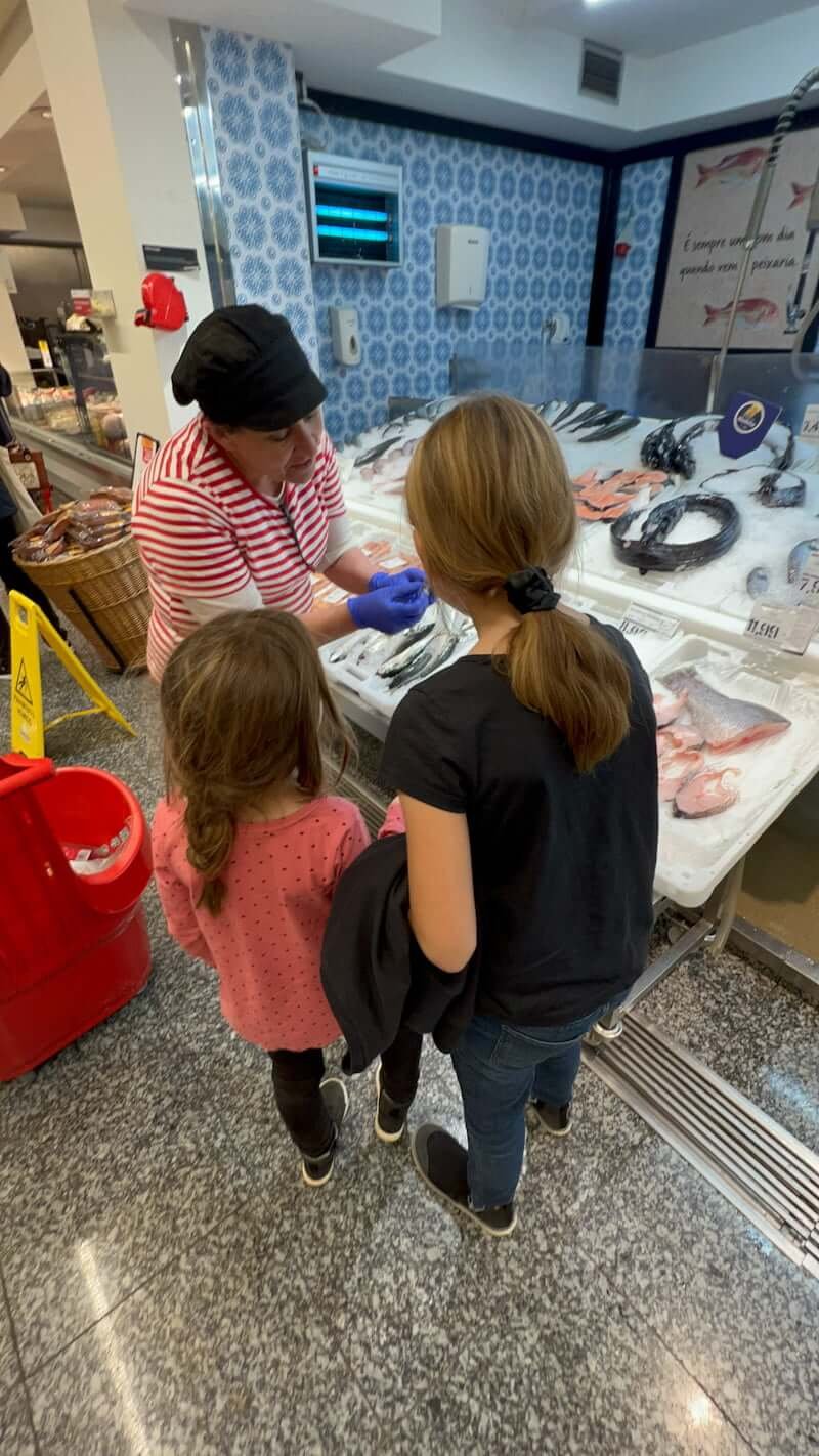 woman showing children seafood in grocery store