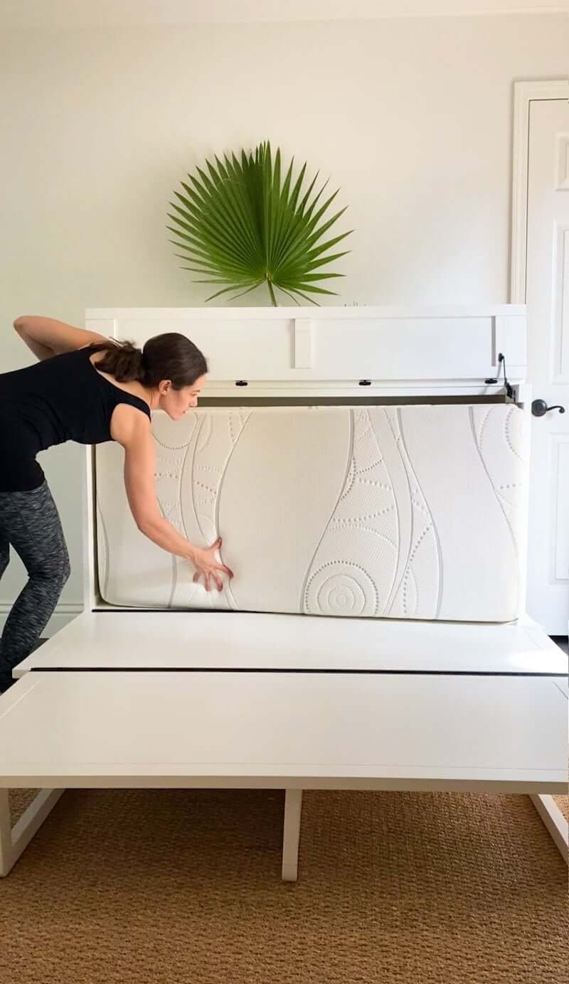 woman folding up guest bed, murphy bed cabinet in guestroom