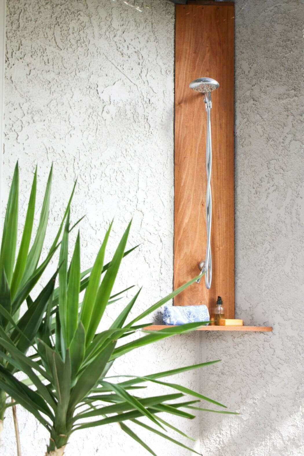 outdoor shower with chrome shower head, shelf, in corner with stucco