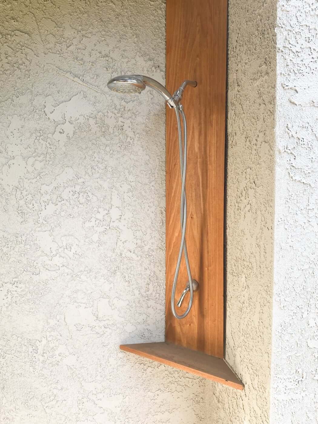 outdoor shower fixture on house in corner, under arbor, made out of chrome