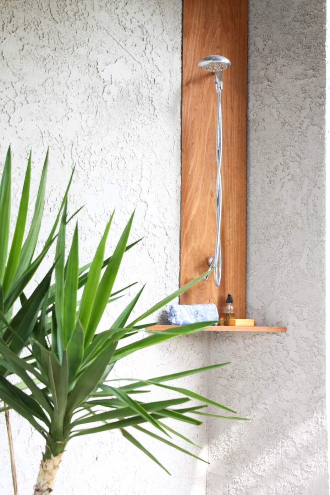 backyard shower made of wood with chrome plumbing fixtures and plants for privacy 