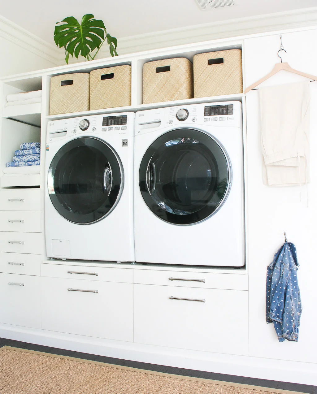 laundry room wall with shelf above and below for baskets, pull-out shelves on side for supplies, white with seagrass rug on wood floor