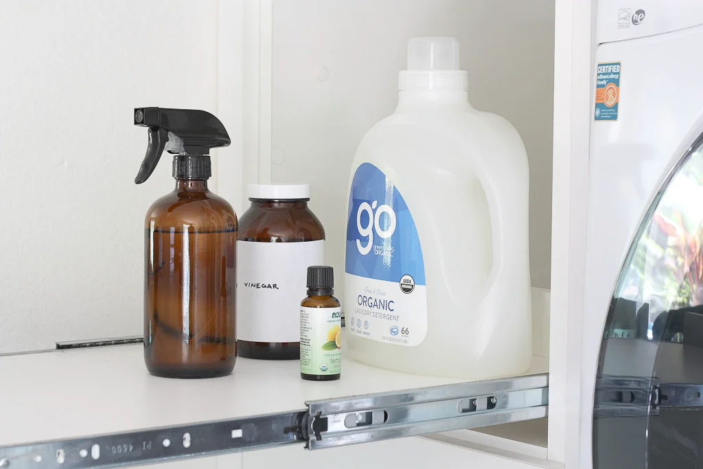 pull-out laundry room shelf with detergent, essential oil and vinegar supplies organized
