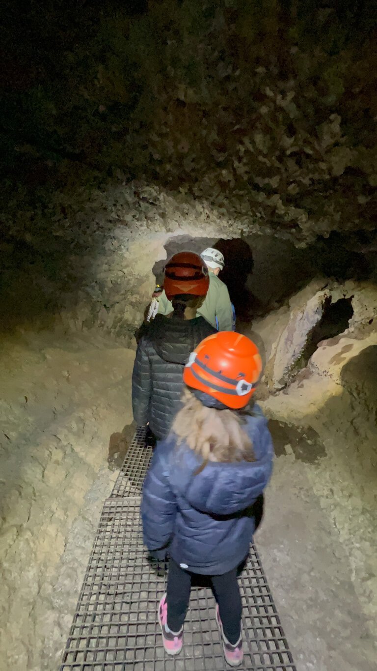 Two girls walking through  a lava tube in Tenerife with guide in front