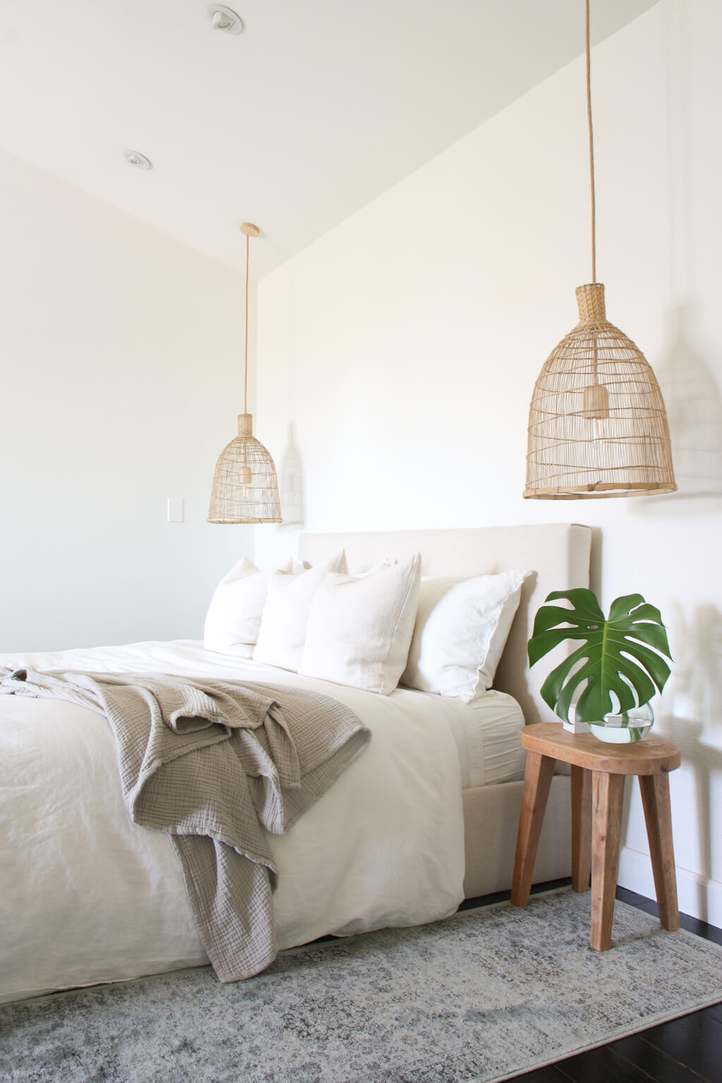 white and cream bedroom with king bed, rug runners, wood side tables and woven seagrass pendants