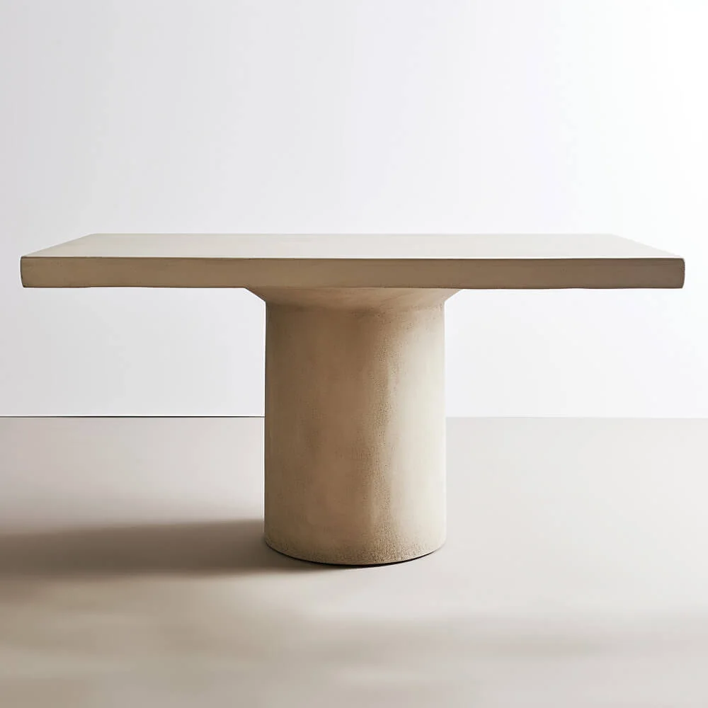 Plaster dining table design with a rectangular top and singular rounded base 