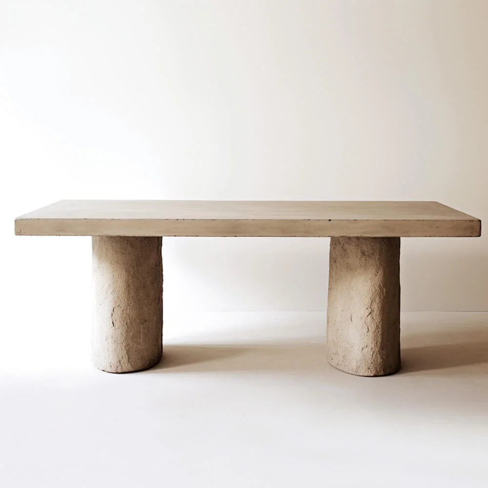 A rectangular, textured table with blended double pedestal base. 