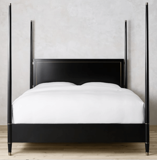Black four poster bed frame design with brass details. White bedding on the bed. 