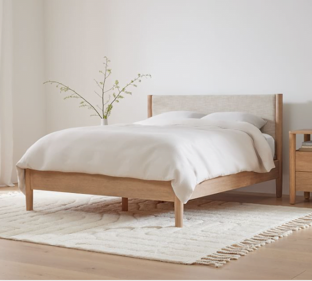 A wooden and upholstered bed frame idea with white bedding and a white rug below the bed. 