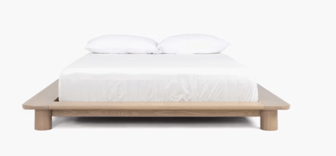 A low profile wooden platform bed frame idea and white bedding on the bed.