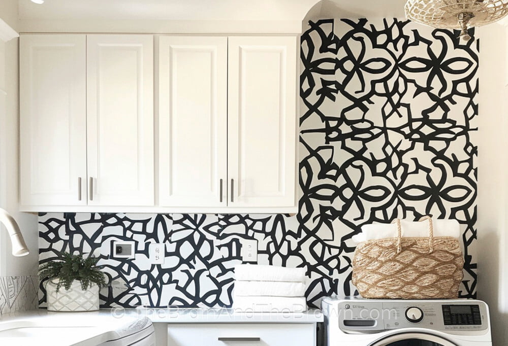 Basement laundry room idea with white cabinetry and a white and black wall stencil. 