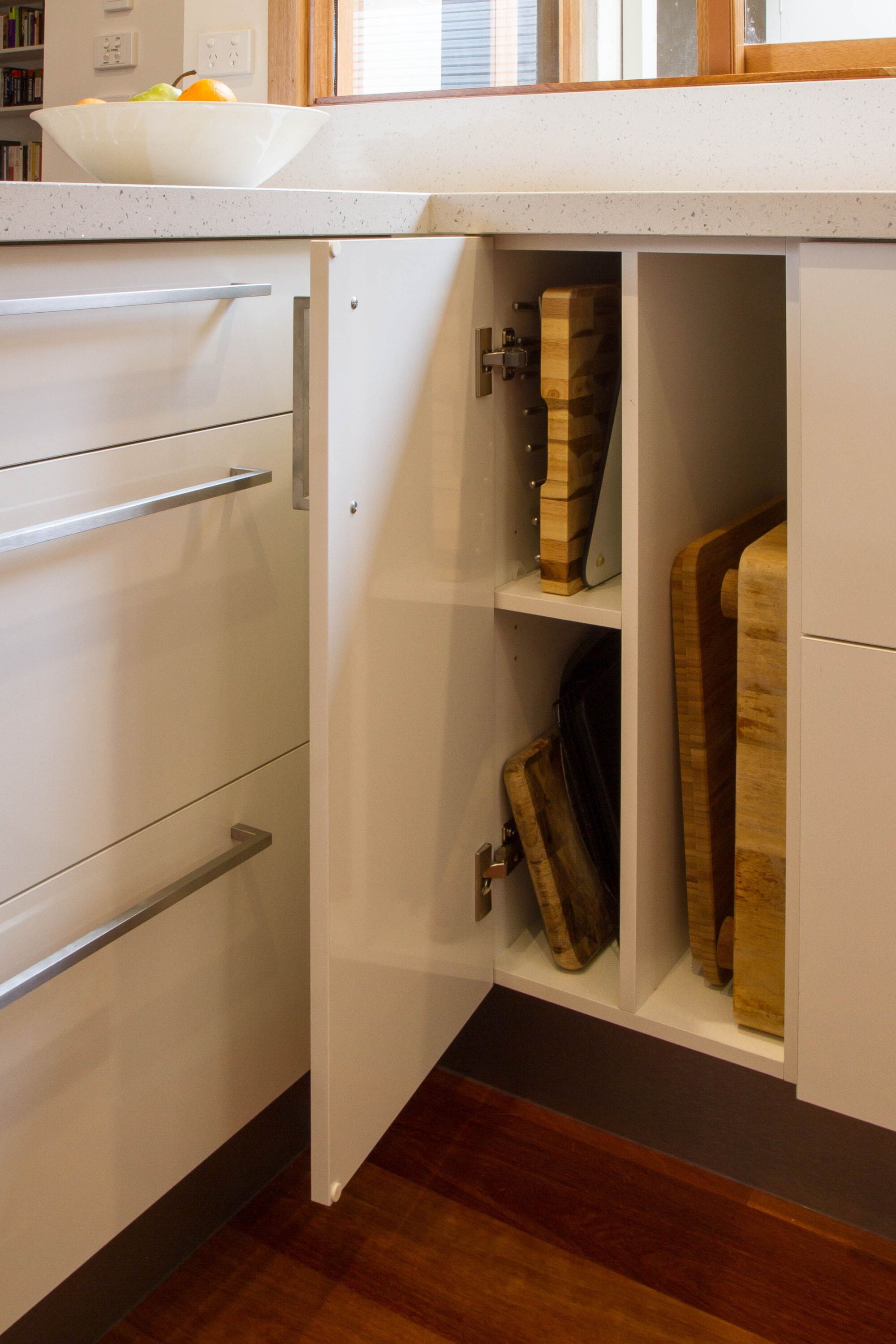 A skinny kitchen cabinet with built-in shelves that stores cutting boards.