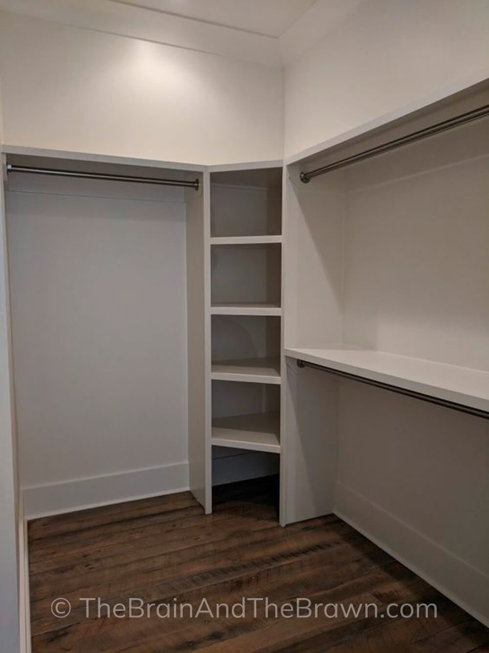 white walk-in closet showing closet corner ideas with shelves in the corners and hanging rods coming off each side, with high closet shelves above and hardwood floors