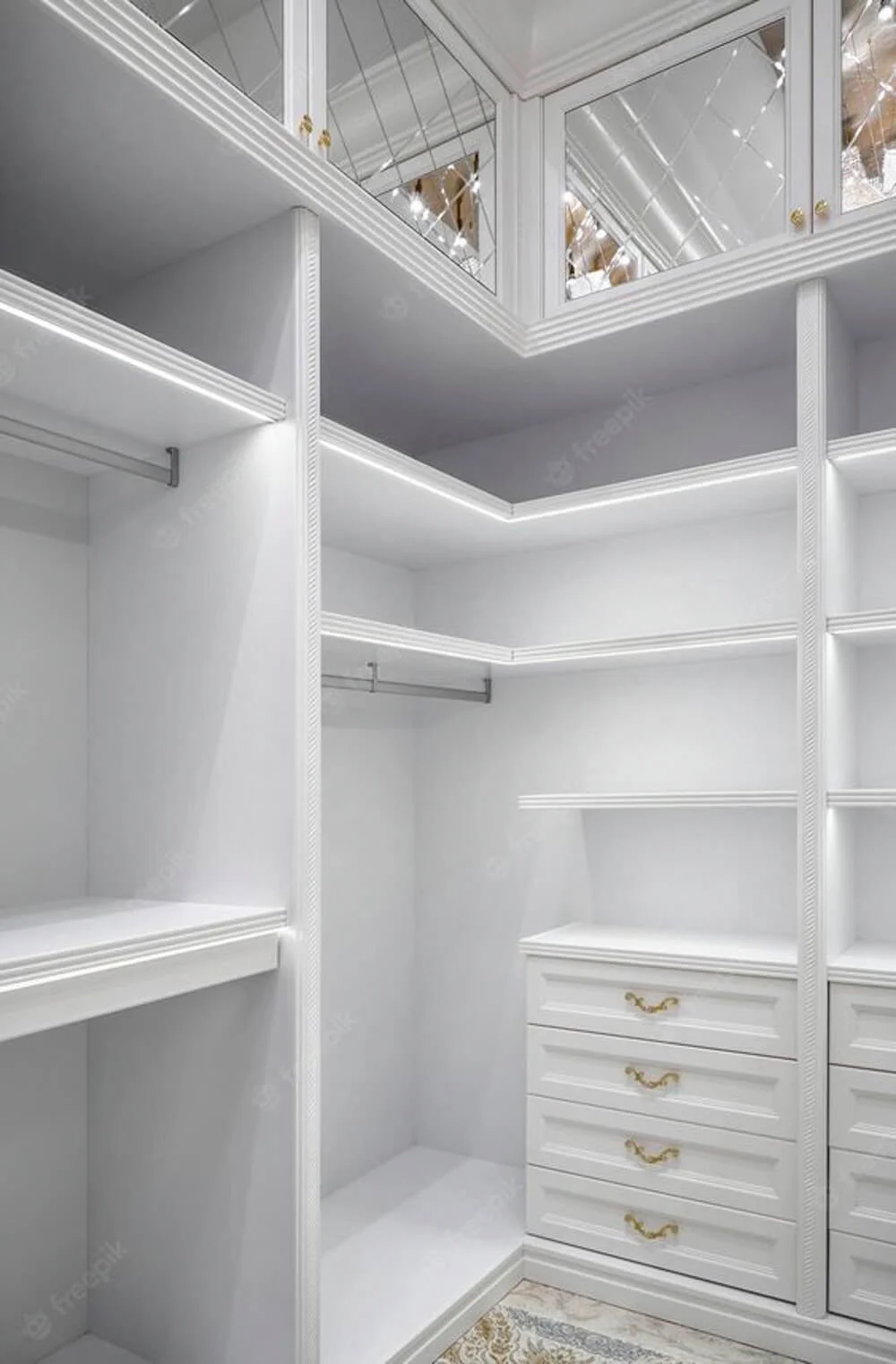 luxe white closet with shelves and hanging rod in corner, mirrored cabinets and drawers