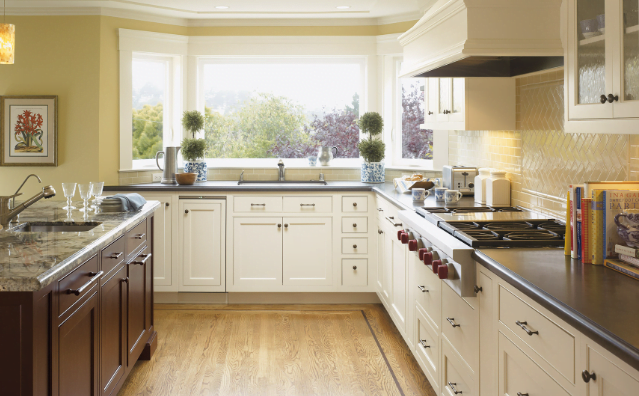 Cream colored kitchen cabinets with black countertops and a wooden kitchen island. 