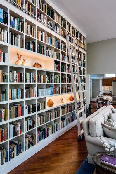 A large wall with white modern built in bookshelves with ladder