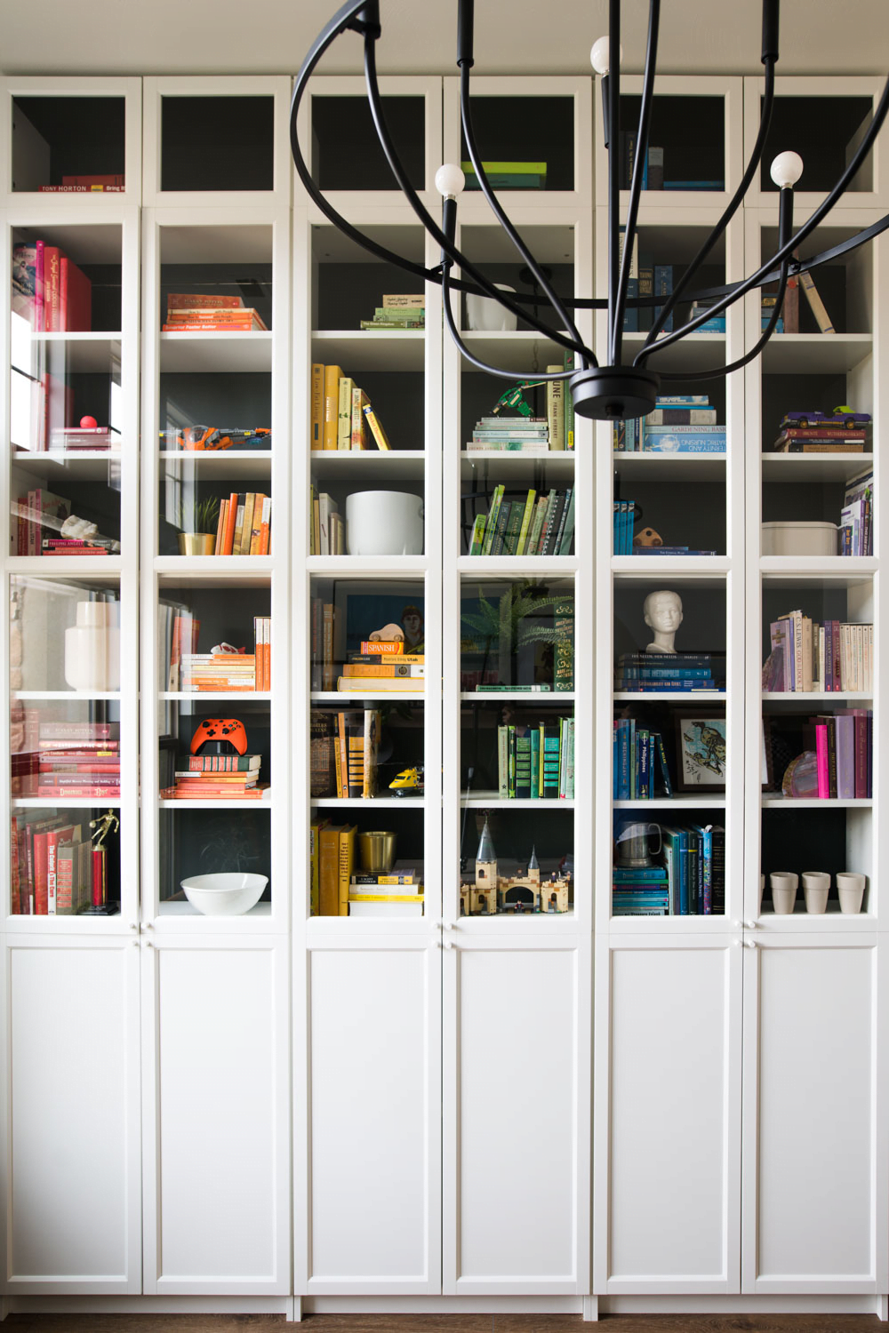 White built in bookshelves with glass cabinet fronts and colorful décor displayed in it