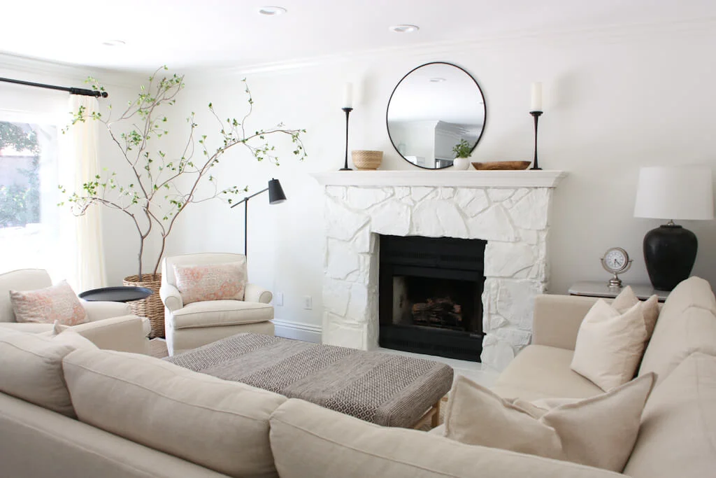 A cozy living room with a stone fireplace, a sectional sofa and two chairs facing the sofa.