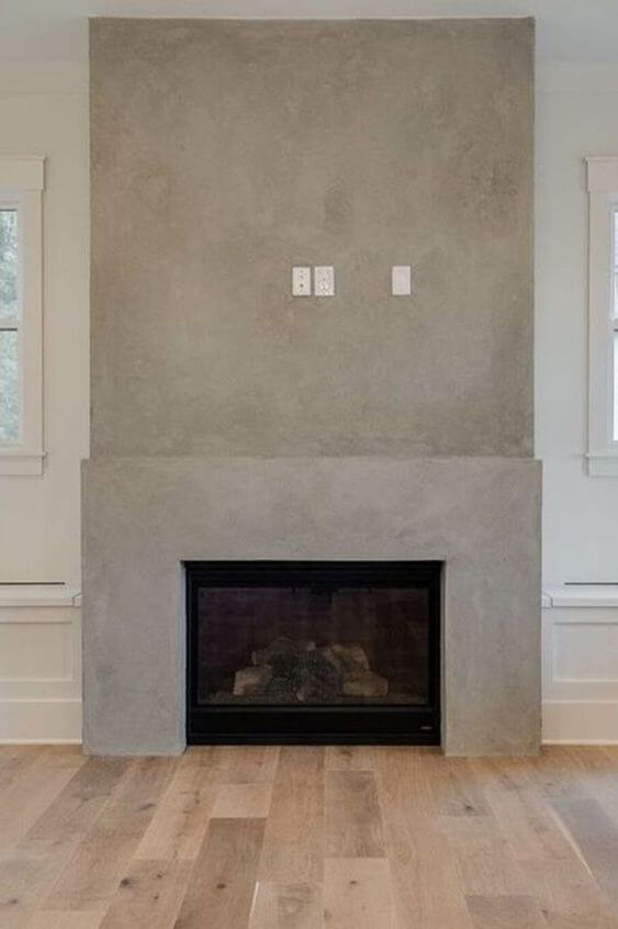 A grey plaster fireplace with electrical to hang a tV above it. 