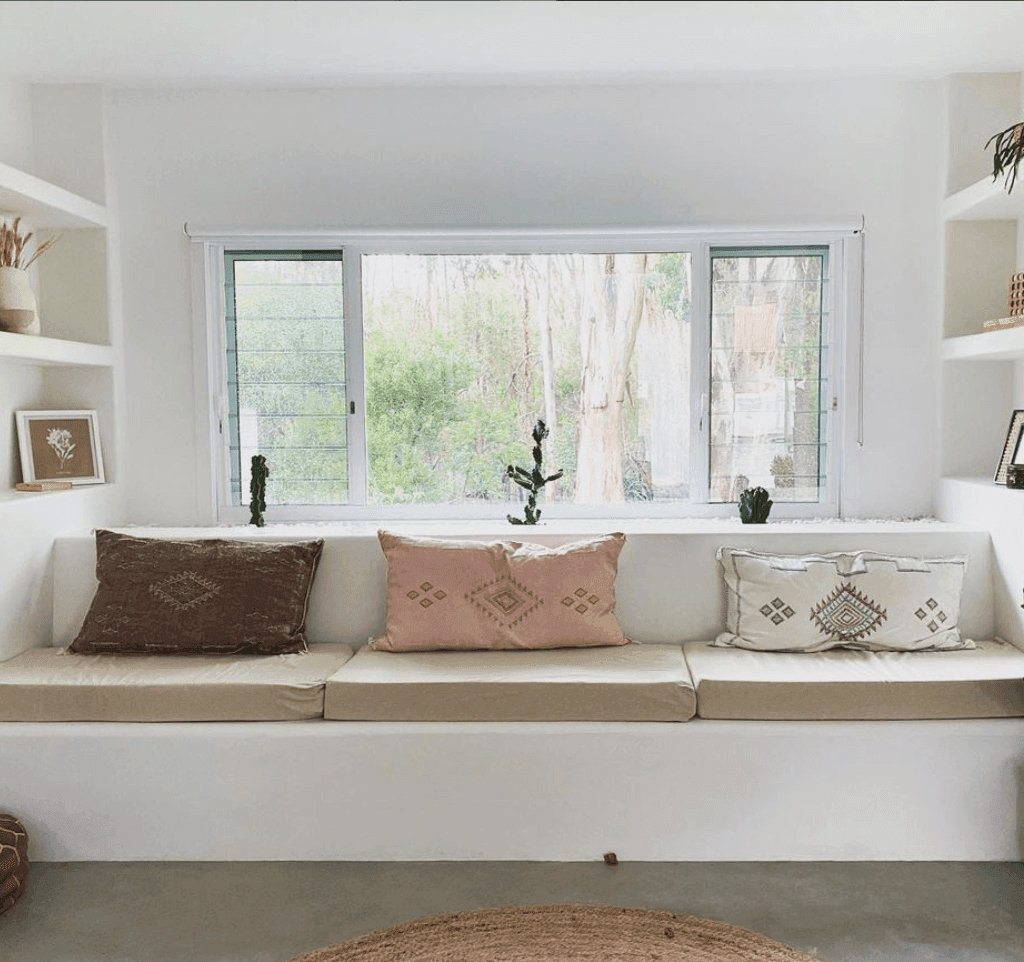 Plaster banquette bench seat in front of large windows 