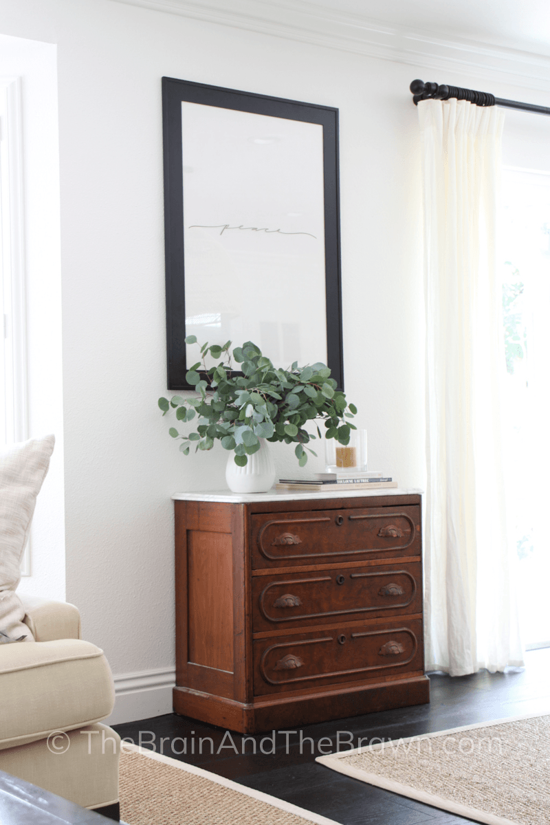 Beautiful antique wooden dresser with a large black frame above used as a DIY wall decor idea by making the frame into a dry erase board